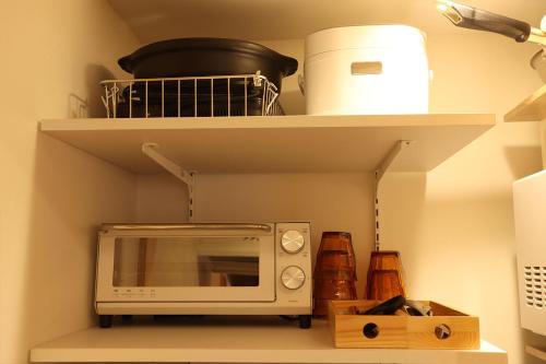 a microwave sitting on a shelf in a kitchen at まほろの宿 - 明日香村のリノベーション古民家一棟貸し in Asuka