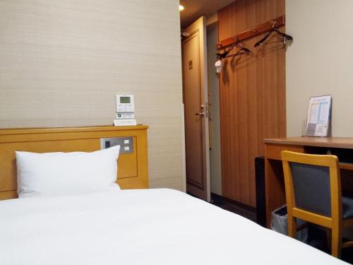 a hotel room with a bed and a desk and a desk at Hotel Route-Inn Hamamatsu Eki Higashi in Hamamatsu