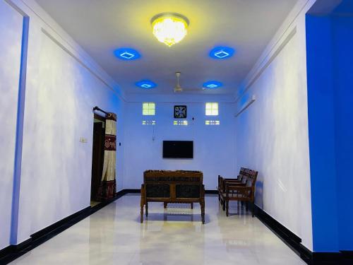 een kamer met stoelen, een tv en blauwe lampen bij Columbus villa in Jaffna