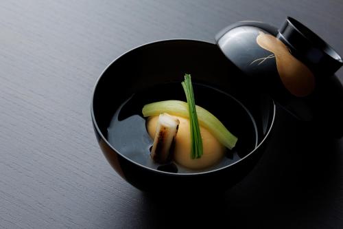 a black bowl with some vegetables in it at Shoraiso in Yamanouchi
