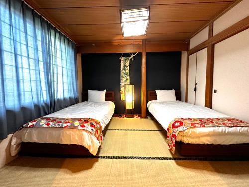 two beds sitting in a room with windows at Economy Hotel Upashi in Asahikawa