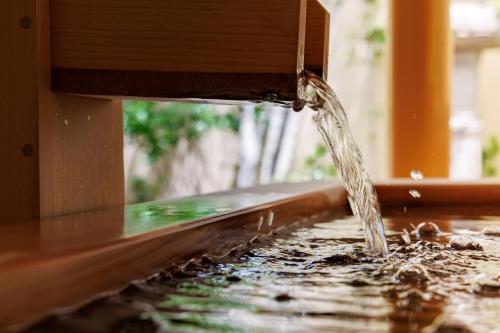 a stream of water coming out of a wooden water fountain at Shoraiso in Yamanouchi