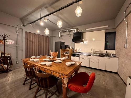 a kitchen with a wooden table and red chairs at Economy Hotel Upashi in Asahikawa