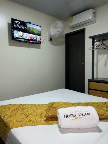 a hotel room with a bed with a tv on the wall at Hotel Olam Confort in Villavicencio