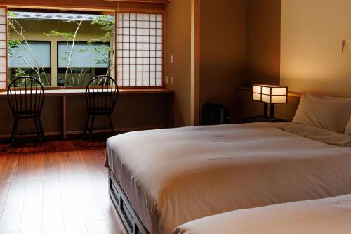 a bedroom with a bed and two chairs and a window at Shoraiso in Yamanouchi