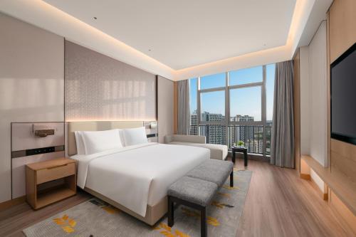 a bedroom with a white bed and a large window at Holiday Inn Guiyang Airport by IHG in Guiyang