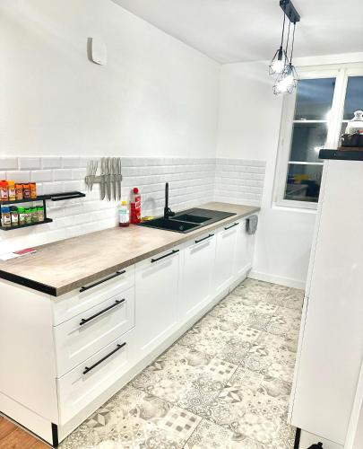 une cuisine avec des armoires blanches et un évier dans l'établissement Appartement chaleureux, à Saint-Florent-sur-Cher