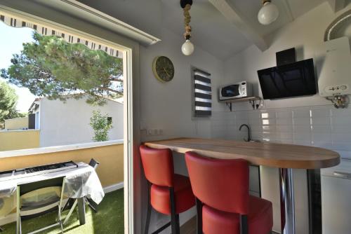 une cuisine avec une table en bois et des chaises rouges dans l'établissement Appartement résidence EUREKA T2-piscine-parking, au Cap d'Agde
