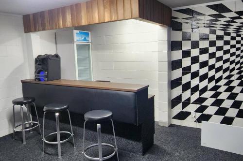 a bar with stools in a room with a checkered wall at Rod & Mandy's Homestead in Rotorua