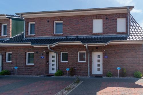a brick building with white doors and a brick driveway at Ferienhaus Domingo in Bensersiel