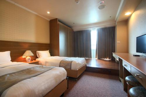 a hotel room with two beds and a flat screen tv at APVC Lukang Resort in Lugang