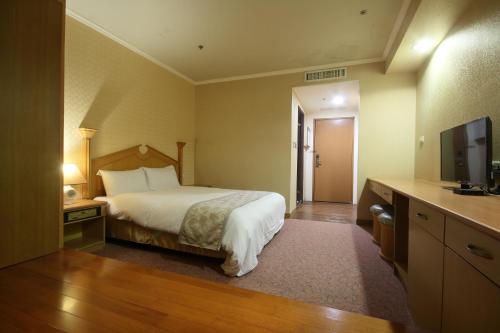 a hotel room with a bed and a flat screen tv at APVC Lukang Resort in Lugang