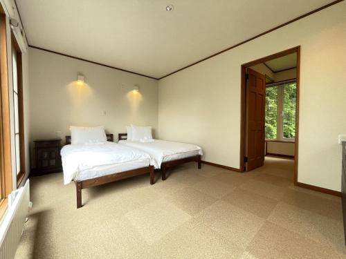 a bedroom with a white bed and a window at Furano Lodge 10 by H2 Life in Furano