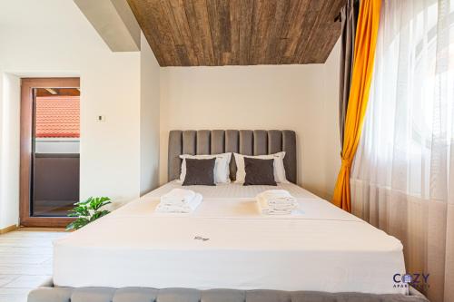a bedroom with a large bed with two towels on it at Cozy Brand New Boutique ApartHotel Brasov in Braşov
