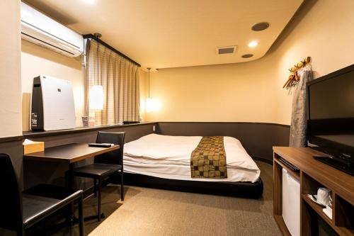 a room with a bed and a desk and a computer at Hotel Double Funabashi in Funabashi