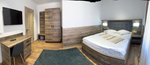 a bedroom with a bed and a flat screen tv at Pensiunea Denisa Stoian in Moieciu de Jos