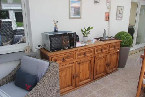 a microwave sitting on top of a wooden cabinet at Le grand jardin de Gaïa et de Rose in Halinghen