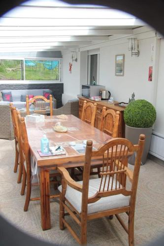 une table et des chaises en bois dans un salon dans l'établissement Le grand jardin de Gaïa et de Rose, à Halinghen