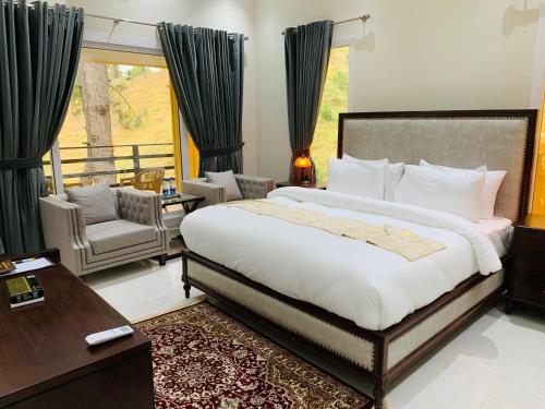 a bedroom with a large bed and a balcony at Hidden Hills Hotel & Resort in Mānsehra
