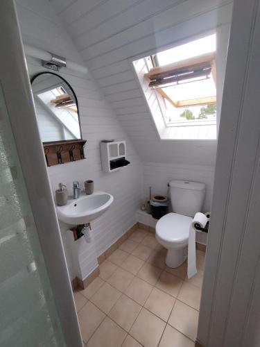 une salle de bain avec des toilettes blanches et un lavabo dans l'établissement Au Pti' Bonheur, à Saint-Coulomb