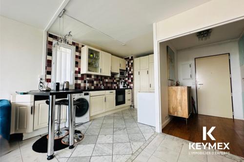 une cuisine avec des armoires blanches et une table à l'intérieur dans l'établissement Chanane, à Épinay-sur-Seine