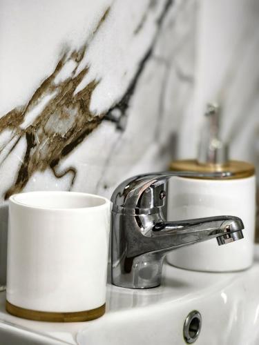 a bathroom sink with a white cup and a faucet at Casa Eliza in Ocna Şugatag