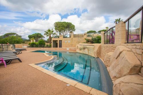 - une piscine avec un mur de roche à côté d'un bâtiment dans l'établissement Camping les Cigales - Tikayan, au Muy
