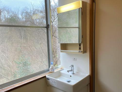 a bathroom with a sink and a window at Dochu Land Shin Onsen in Awa