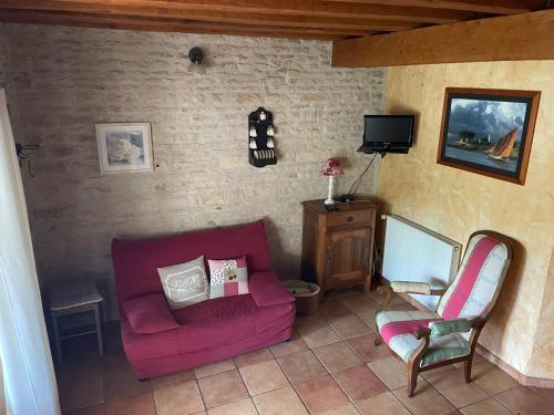 a living room with a pink couch and a chair at Sous l olivier in Tusson