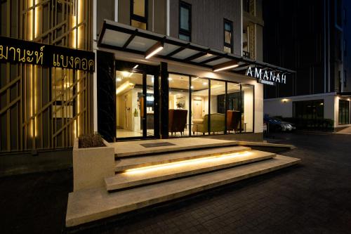 a building with glass doors on a street at night at Amanah Bangkok Hotel in Bangkok