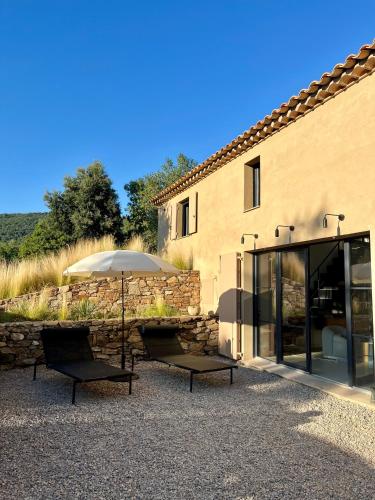 2 chaises et un parasol devant un bâtiment dans l'établissement Les Plaines, à La Môle