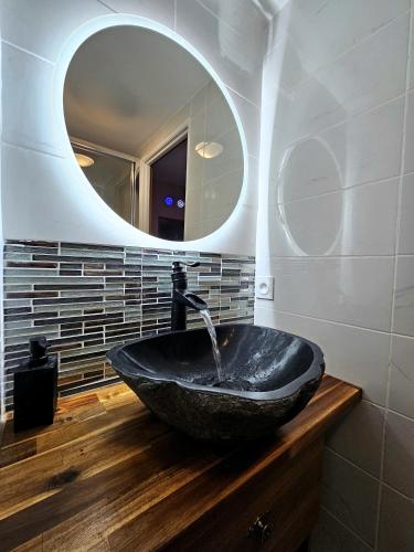 une salle de bain avec un lavabo noir et un miroir dans l'établissement Tout confort ! Ville, Calme, Cinéma privé, Climatisation, Parking, WiFi, à Carcassonne