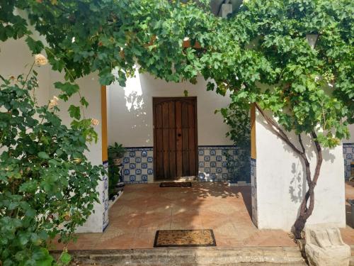 un ingresso di una casa con un albero e una porta di Cortijo Las Cruces Guillena - Sevilla a Guillena