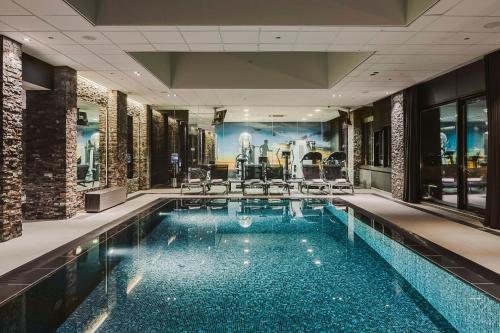 a large swimming pool with chairs and tables in a building at Van der Valk Hotel Dordrecht in Dordrecht
