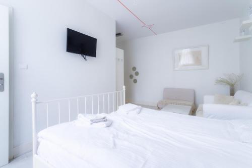 a white bedroom with a bed and a tv on the wall at Villa Superiq Victus Sopot Walk to the Pier by Noclegi Renters in Sopot