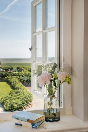 a vase of flowers sitting on a window sill with books at Strandvogtei Sylt in Rantum