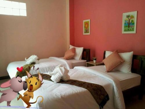 a bedroom with three beds with stuffed animals on them at โรงแรมตะวันไท in Ban Krabi Yai