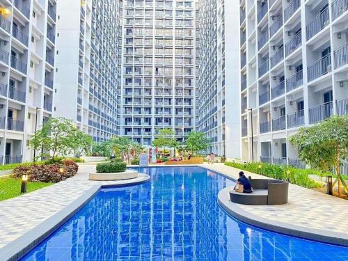a person sitting in a chair next to a swimming pool in a building at E & R Staycation Condotel near Mall of Asia in Manila
