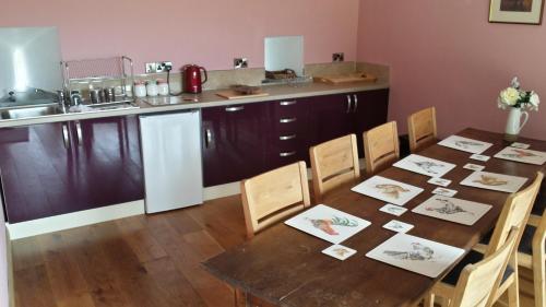 a kitchen with a wooden table with chairs and a kitchen counters at Rhostwarch in Eglwyswrw