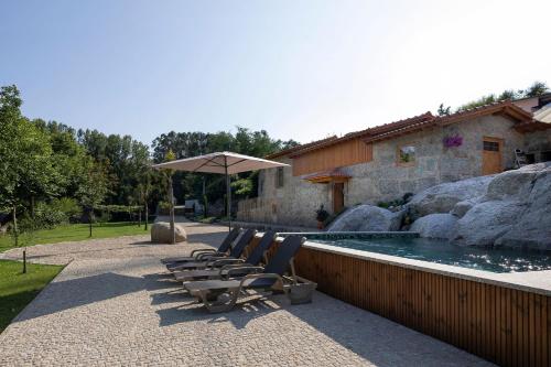 a group of chairs and an umbrella next to a pool at Casa Ponte de Espindo in Lousada