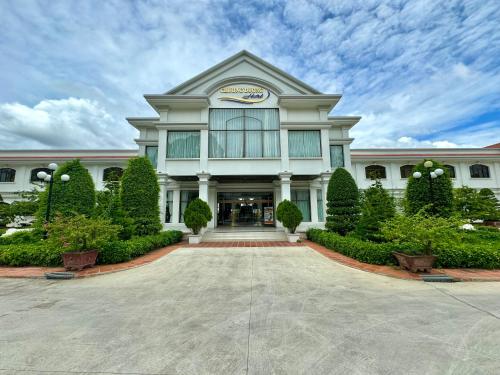 a large white building with bushes and trees at CHUONG DUONG HOTEL in My Tho