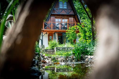 a house with a pond in front of it at Erdő Lelke Vendégház: mesebeli, erdőszéli faház panorámával in Nagymaros