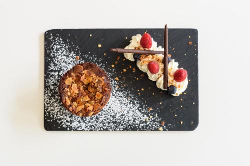 a plate with a dessert and a cake with strawberries at Clarion Aparthotel Toulouse Le Parc de l'Escale in Toulouse