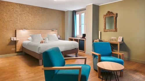 a bedroom with a bed and two blue chairs at Grand H&ocirc;tel Dauphin&eacute;, Boutique H&ocirc;tel & Suites in Toulon