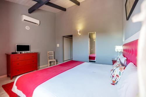 a bedroom with a large bed with a red dresser and a tv at Quinta dos Is in Algoz