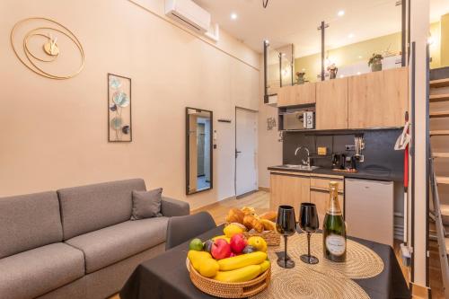 un salon avec un canapé et une table avec un bol de fruits dans l'établissement ADIRA Marseille Montgrand 2 étoiles, à Marseille