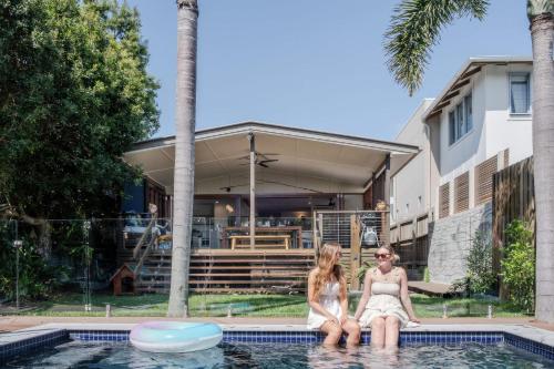 two women sitting in the pool in front of a house at 'The Otto' At Moffat Beach in Caloundra