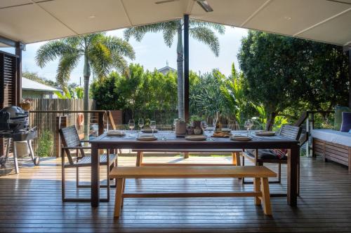 a dining table and chairs on a deck with an umbrella at 'The Otto' At Moffat Beach in Caloundra
