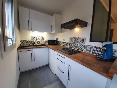 une cuisine avec des armoires blanches et des comptoirs en bois dans l'établissement La citadine, à Cholet