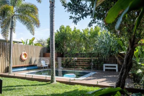 a garden with a swimming pool and palm trees at 'The Otto' At Moffat Beach in Caloundra